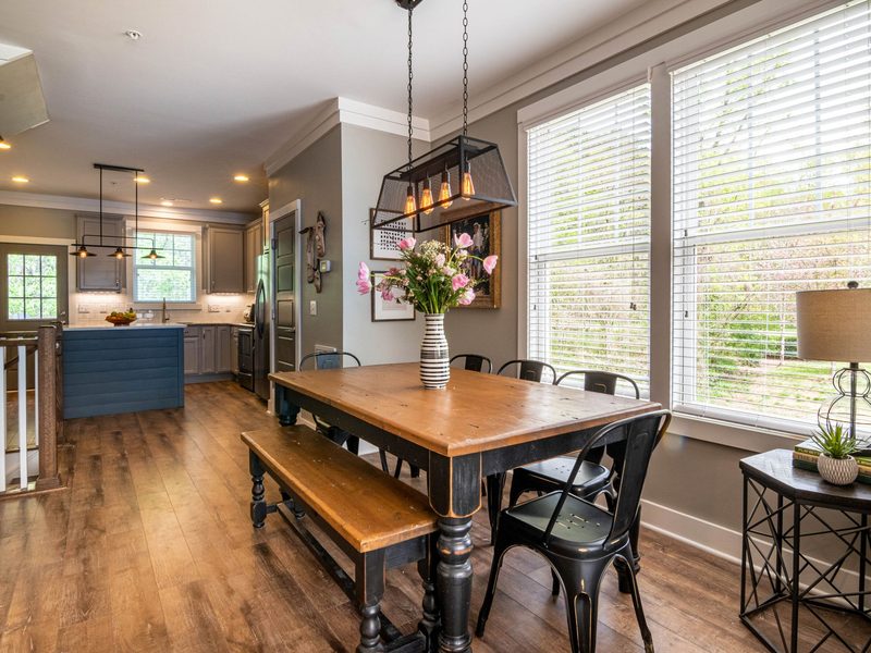 A dining room with a wooden table set beside large windows